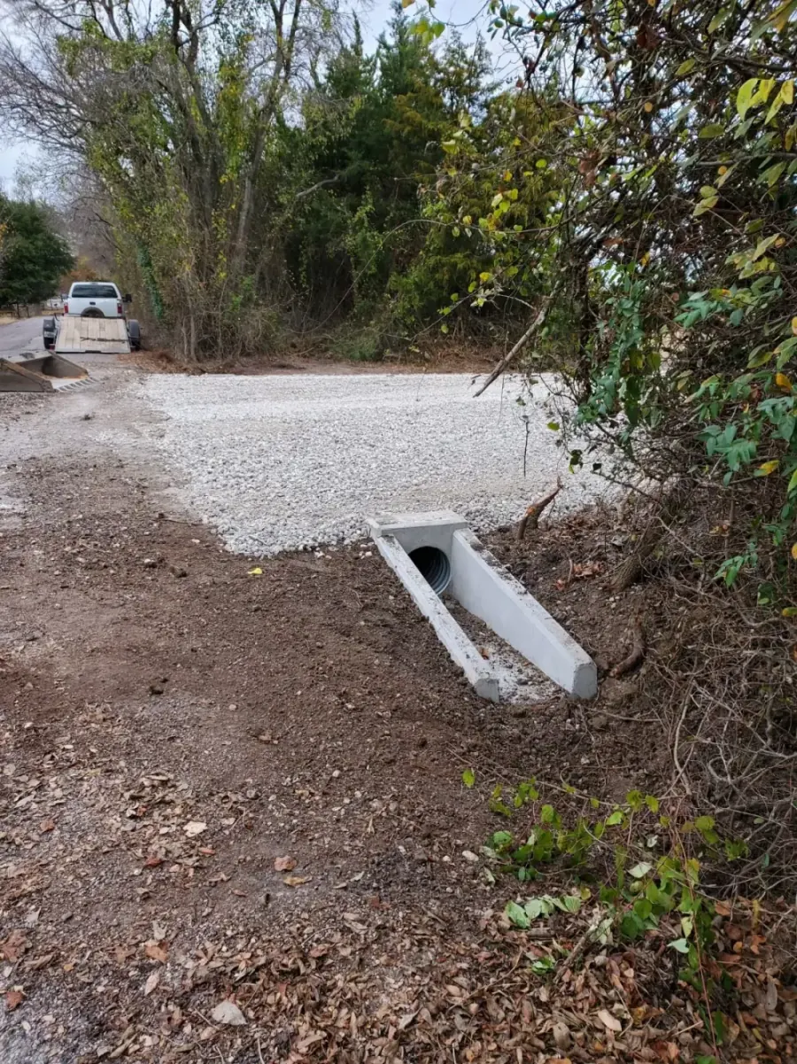 Concrete headwall culvert draining a gravel driveway into a wooded lot in North Texas