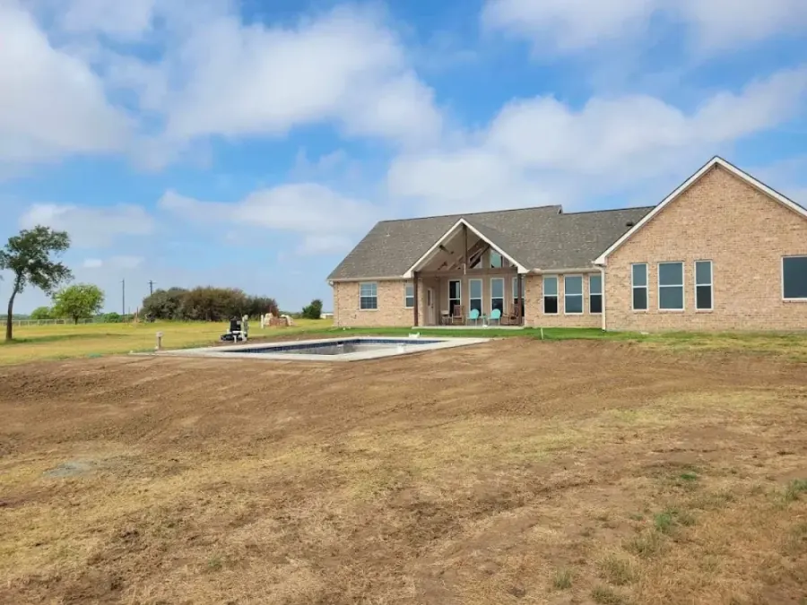 Graded acreage behind a large custom brick home in Prosper TX after site prep and finish grading