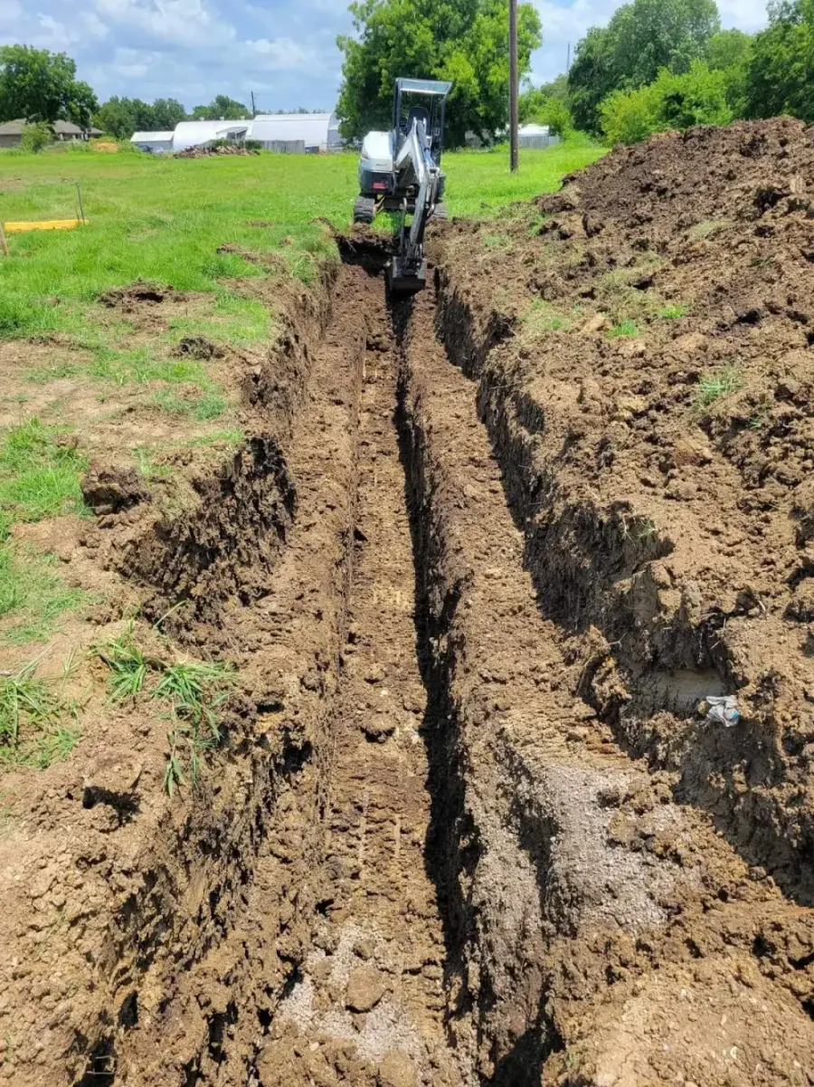 Skid-steer digging a long straight utility trench across a pasture in Aubrey TX